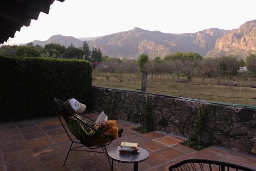 a person sitting in a hammock with a table and mountains at Villas Mexiko in Tepoztlán