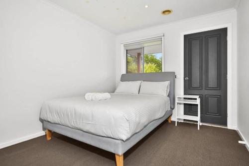 1 dormitorio con cama blanca y puerta negra en Your Home Retreat in Maribyrnong, en Melbourne