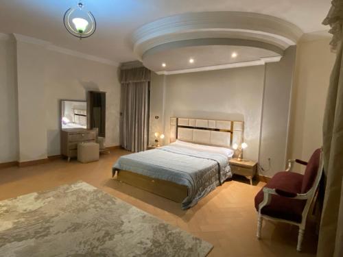a large bedroom with a bed and a chair at The Gardenia Villa Chic Escape with Pool in 6th Of October