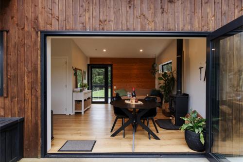 a dining room and living room with a sliding glass door at Hidden Springs Retreat - Karangahake Mountain View in Karangahake