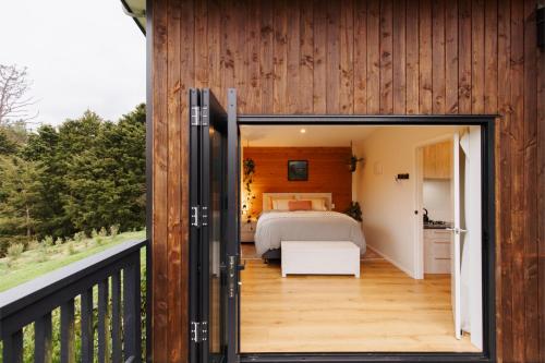 a bedroom with a bed on a balcony at Hidden Springs Retreat - Karangahake Mountain View in Karangahake