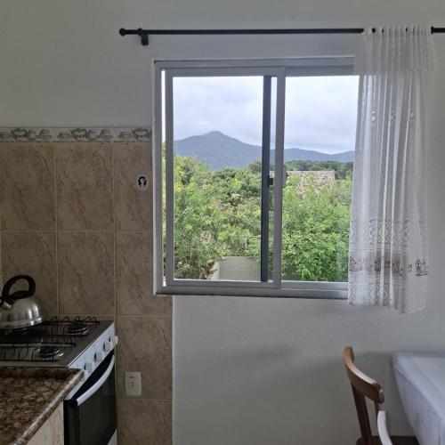 a kitchen with a window with a mountain view at Residencial Caramujo in Florianópolis