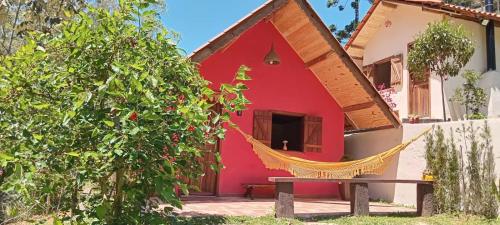 a red house with a hammock in front of it at Chalé Refúgio dos Gnomos in Visconde De Maua