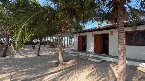 a small building on the beach with palm trees at Casa Monan, Atins beach in Atins