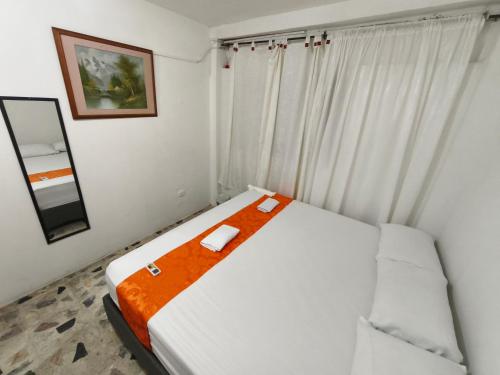 a bedroom with a white bed with an orange blanket at Cabaña Gaia Rodadero in Santa Marta