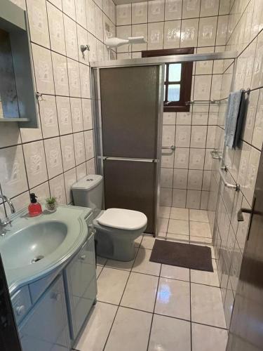 a bathroom with a toilet and a sink and a shower at Casa de veraneio 2 dormitórios in Torres
