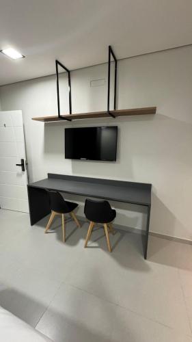a black desk with two chairs in a room at Studios Gago 167 in Suzano