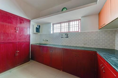 a large kitchen with red cabinets and a window at Hotel O JJ Residency in Chennai