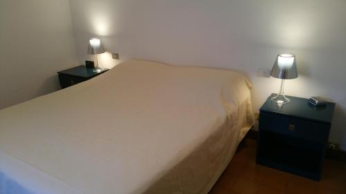 a bedroom with a bed and two night stands with lamps at Villetta Punta Ala in Punta Ala