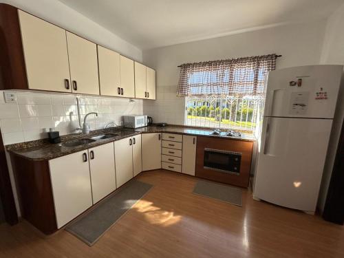 Una cocina con gabinetes blancos y un refrigerador blanco. en Morada dos Pomares, en Pomerode