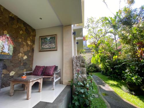 a porch with a bench and a table at ThreeWin Homestay in Ubud