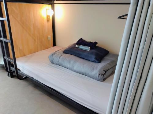 a bed in a bunk bed with a pillow on it at TONARINO Backpackers Hostel Free Breakfast in Kobe