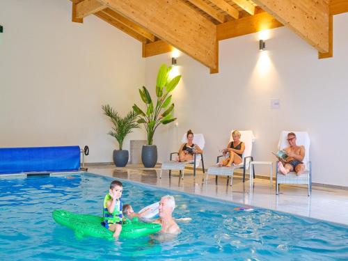 a child in the swimming pool with a group of people sitting at Charming Alps Apartment in Abondance