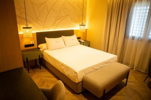 a bedroom with a white bed and a chair at Hotel Macami in El Carpio