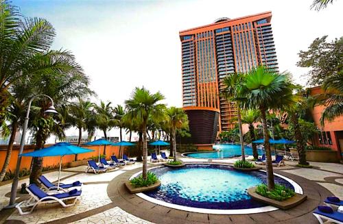 une piscine avec des chaises et des palmiers ainsi qu'un hôtel dans l'établissement KL Exclusive Service Suites at Times Square Kuala Lumpur Malaysia, à Kuala Lumpur