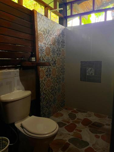 a bathroom with a toilet and a tile floor at Ecohotel Iraka Cabañas Privadas en Selva y Playa in Bahía Solano