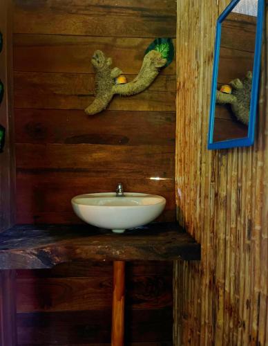 a bathroom with a white sink on a wooden wall at Ecohotel Iraka Cabañas Privadas en Selva y Playa in Bahía Solano