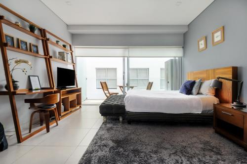 a bedroom with a bed and a desk and a tv at Alure Condesa in Mexico City