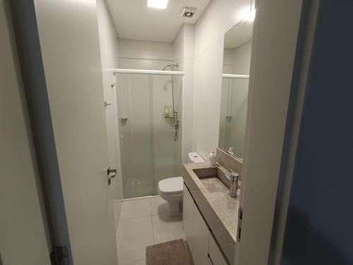 a bathroom with a toilet and a glass shower at Duplex lindo sofisticado in Governador Celso Ramos