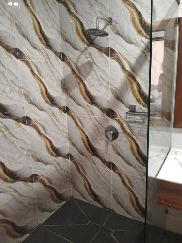 a bathroom with a shower with a marble wall at Villa Santai Mentawai in Tua Pejat