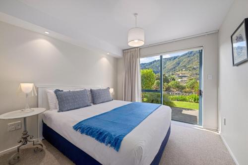 a bedroom with a bed and a large window at Marina Edge Marlborough Sounds Apartment in Waikawa