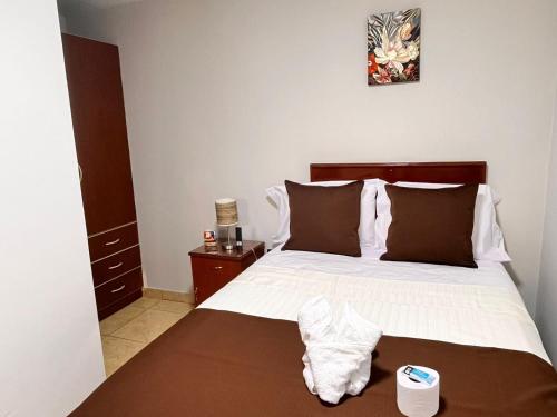 a bedroom with a large bed with white sheets and brown pillows at Casa Baraquel in Arequipa