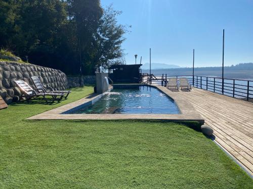 una piscina en una terraza con sillas y mesa en Lodge Colbún, en Colbún Alto