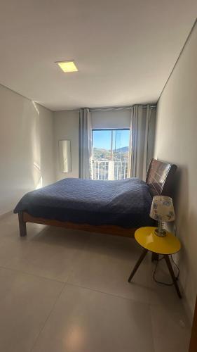 a bedroom with a bed with a window and a table at Apê da Bella seu refúgio no Caparaó in Alto Caparao