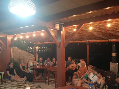 a group of people sitting around a table in a restaurant at Three Ken Homestay & Cafe in Manado