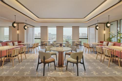 a restaurant with tables and chairs and windows at Hilton Garden Inn Chongqing Yubei Central Park in Chongqing