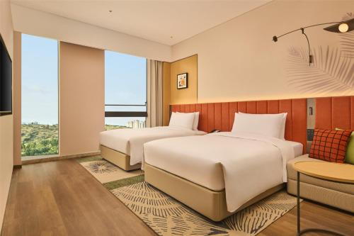 two beds in a hotel room with a view at Hilton Garden Inn Chongqing Yubei Central Park in Chongqing