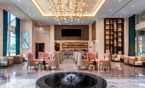 a lobby with a bar and chairs and a tv at Blossom Hotel Houston, Curio Collection by Hilton in Houston