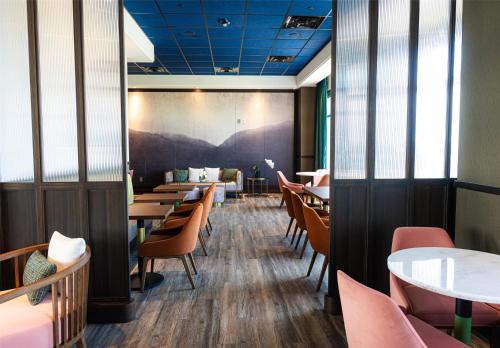 a dining room with tables and chairs and a mural at Blossom Hotel Houston, Curio Collection by Hilton in Houston