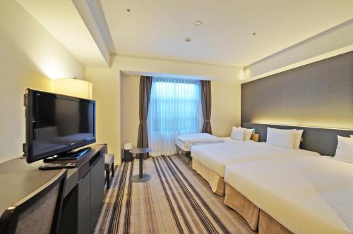 a hotel room with two beds and a flat screen tv at Chisun Grand Takayama in Takayama