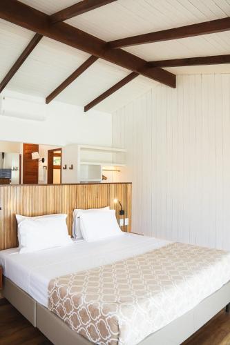 a bedroom with a large bed with white sheets at Vila Corada in Pipa