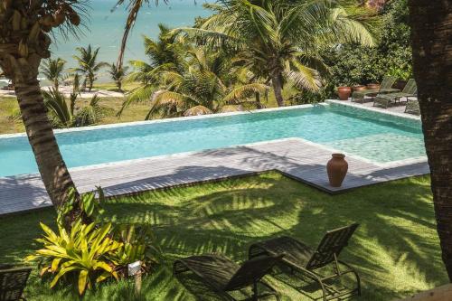 a swimming pool with two chairs and a vase in a yard at Vila Corada in Pipa