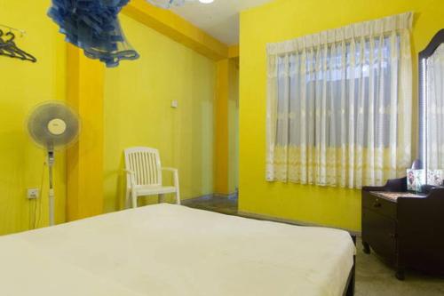 a bedroom with yellow walls and a bed and a chair at Candy Home in Kandy
