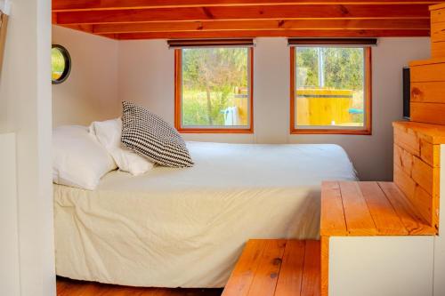 a bed in a small room with two windows at Refugio Campestre, Cabaña con Tinaja Opcional 