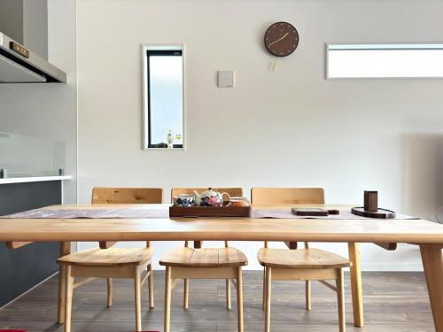 a dining room table with chairs and a clock on the wall at The YAMAGUCHI in Inzai