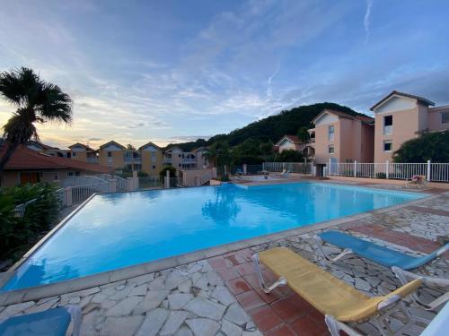 a large swimming pool with two lounge chairs next to it at Studio Melisyle in Sainte-Anne