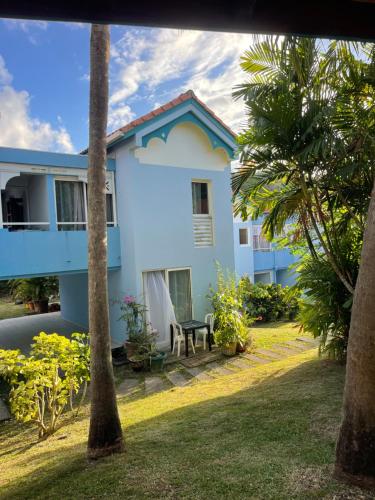 a blue and white house with palm trees at Studio Melisyle in Sainte-Anne