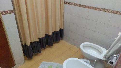 ein Badezimmer mit Toilette und Duschvorhang in der Unterkunft Casa Grande con pileta próximo kempes, ferial, Córdoba in Cordoba