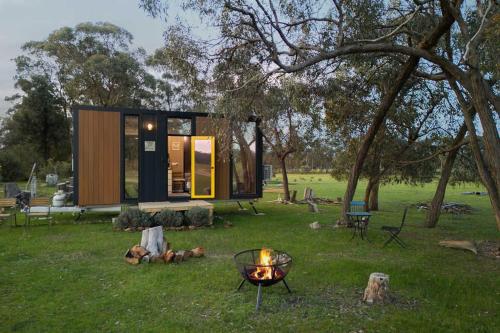 a tiny house in a field with a fire at Sheryl's Place by Tiny Away