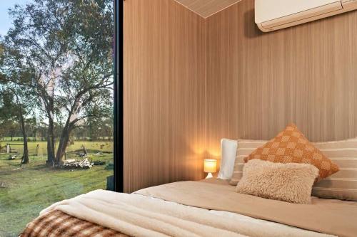 a bedroom with a bed with a large window at Sheryl's Place by Tiny Away