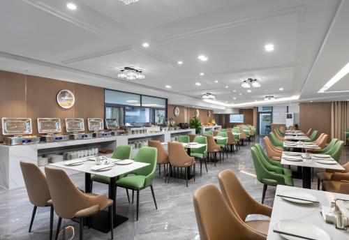 a dining room with tables and green chairs at Days Inn by Wyndham Zhuhai Qinglv Road in Zhuhai