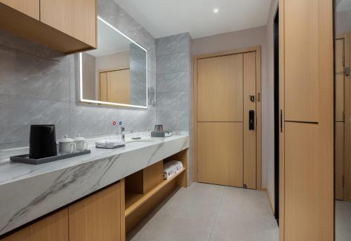 une salle de bain avec un lavabo et un miroir dans l'établissement Ramada Encore by Wyndham Enshi Huaxi Valley, à Jianshi