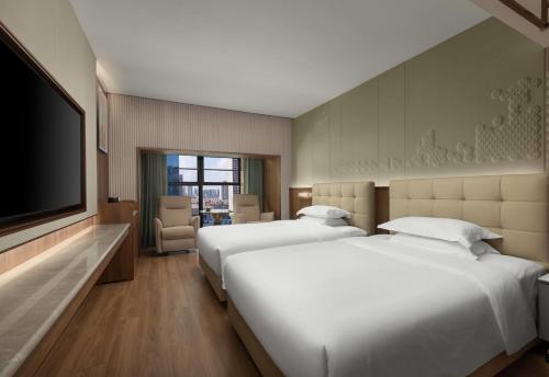 two beds in a hotel room with a flat screen tv at Days Inn by Wyndham Changsha Yuanda Road in Changsha