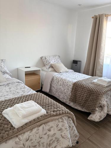 a bedroom with two beds and a table and a window at Athlon Apartment in Río Gallegos