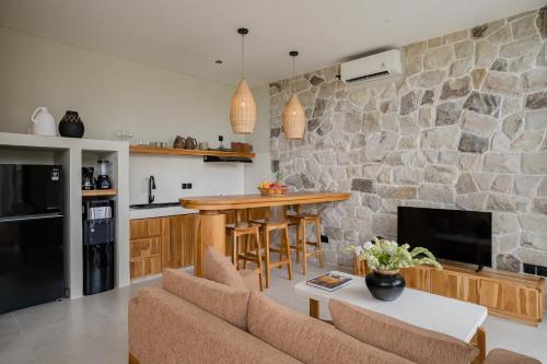 a kitchen and living room with a stone wall at Sawah Villas Pantai Lima in Pererenan