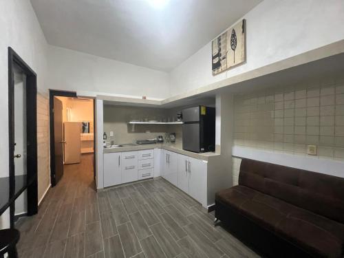 a kitchen with white cabinets and a couch in a room at Alameda Suites & CAS - Centro Monterrey in Monterrey